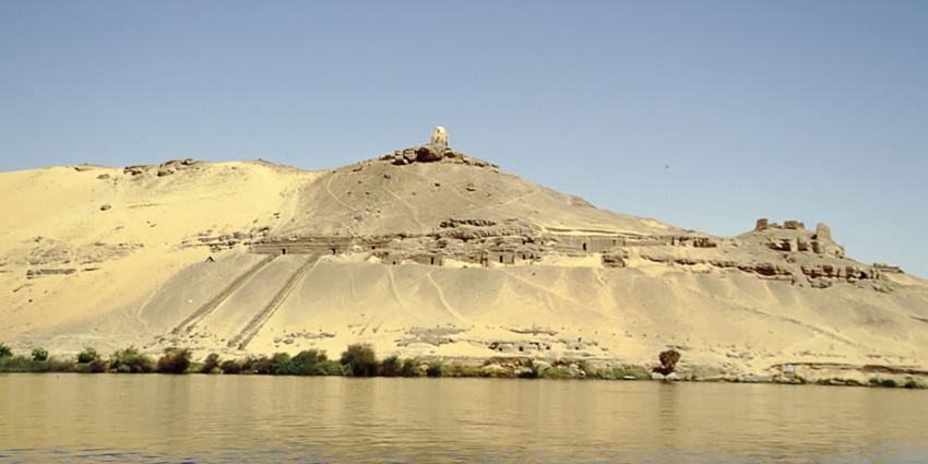 An image of the Tombs of the Nobles in Aswan, Egypt, showcasing ancient rock-cut tombs along the Nile.