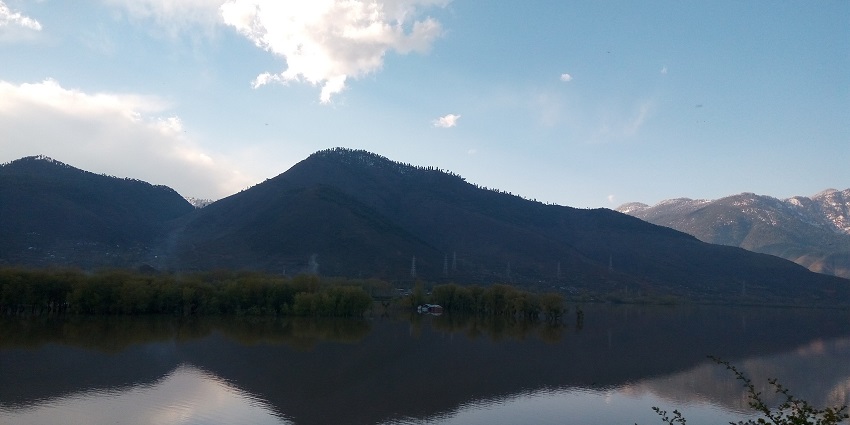 Wular lake with a still water body and hills and mountains partially covered in snow