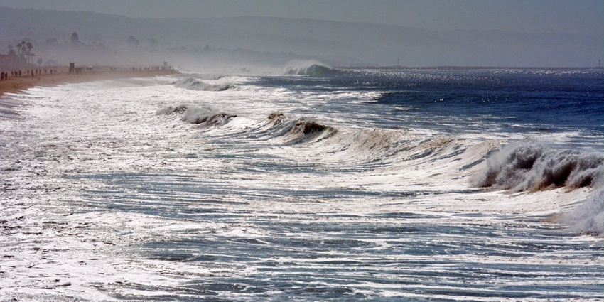 Powerful ocean wave curling into a tube near the shore with white foam spraying high