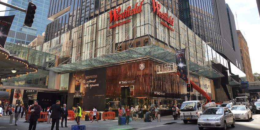 Image of Westfield Sydney with a busy urban street, retail stores, shoppers, cars, and traffic.
