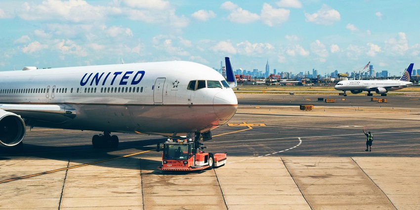 Couple of commercial aeroplanes parked with white and dark blue designs and a man standing