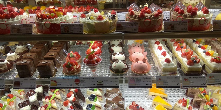 Bakery display with cakes, pastries, and adorable animal-shaped desserts topped with fruit
