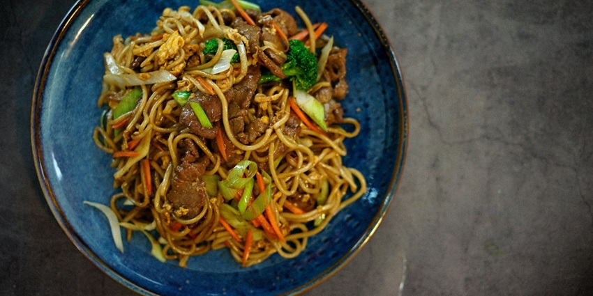 Image of a plate of noodles with meat and egg fried - served on a plate