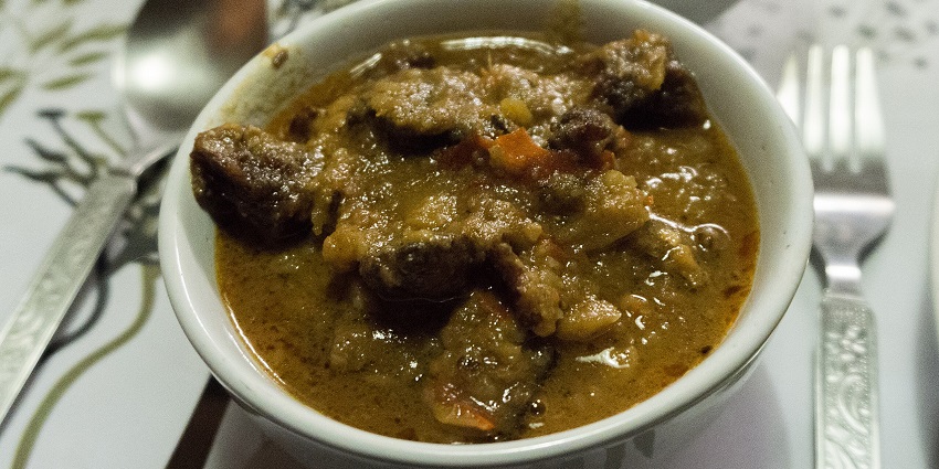 A traditional Naga meal with rice, vegetables, chutney, and smoked meat on a plate.