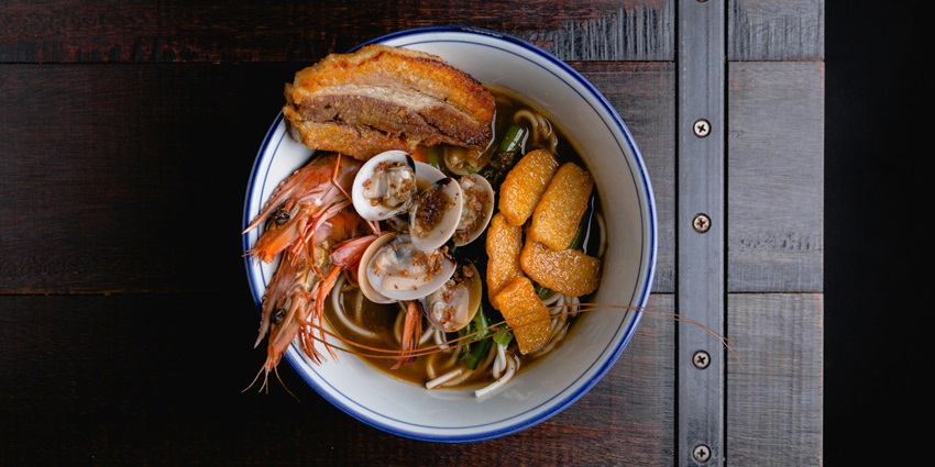Image a bowl of noodles with seafood and soup served in a bowl