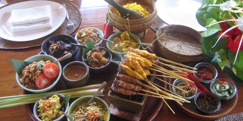 Traditional Indonesian feast with satay skewers, rice, and assorted side dishes.