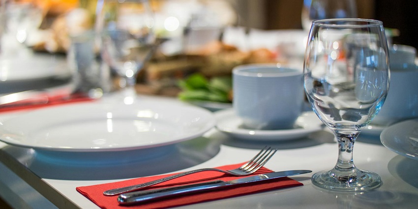An image showing neatly arranged cutlery and glassware in a formal restaurant setting.