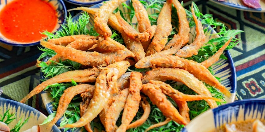Perfectly fried Thai fish with crispy skin, served with basil, red chillies, and dipping sauce, near Sukhothai Historical Park.