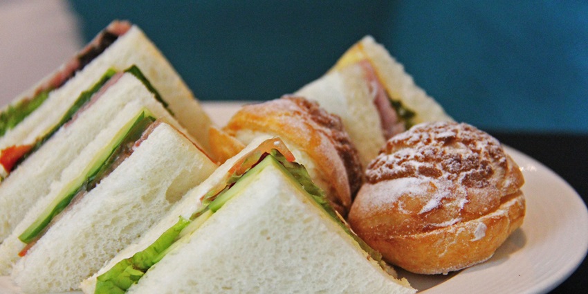 A plate displaying neatly arranged sandwiches with fresh fillings and sweet pastries.