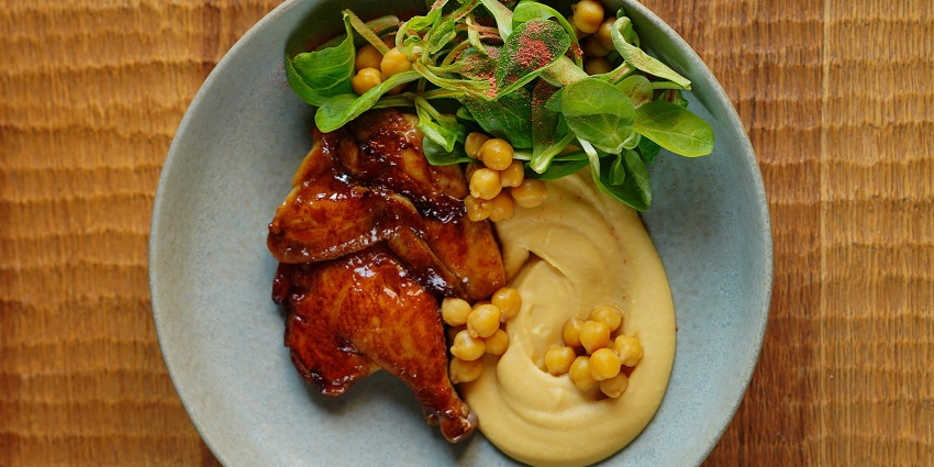 Enjoy a plate of delicious grilled chicken and hummus, served with fresh herbs.
