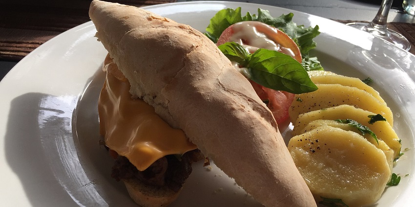 A veggie Philly cheesesteak with peppers and melted cheese, and a soft hamburger roll.