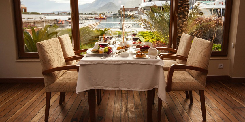 An image of a fine dining setup with white tablecloth, scenic marina view, red wine, similar