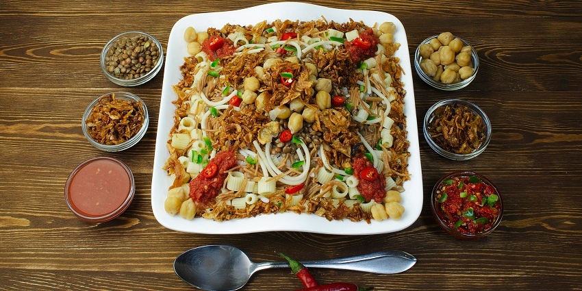 A plate featuring layers of rice, macaroni, lentils, and chickpeas, with fried onions