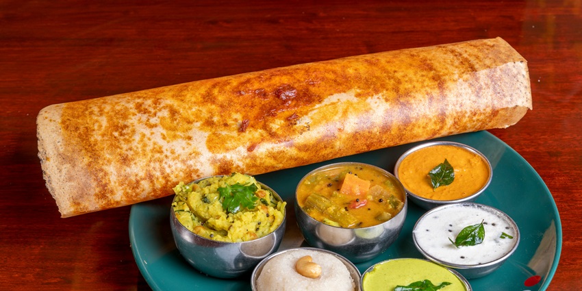 Traditional South Indian meal with dosa, chutney, and sambar served on a banana leaf.
