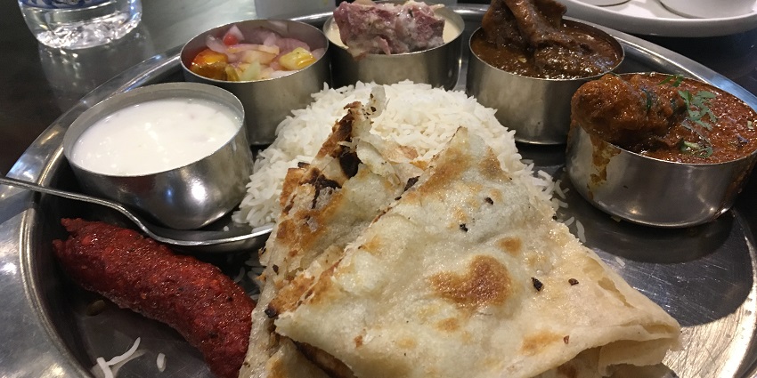 A picture of a non veg thali served food in small containers and round steel plate