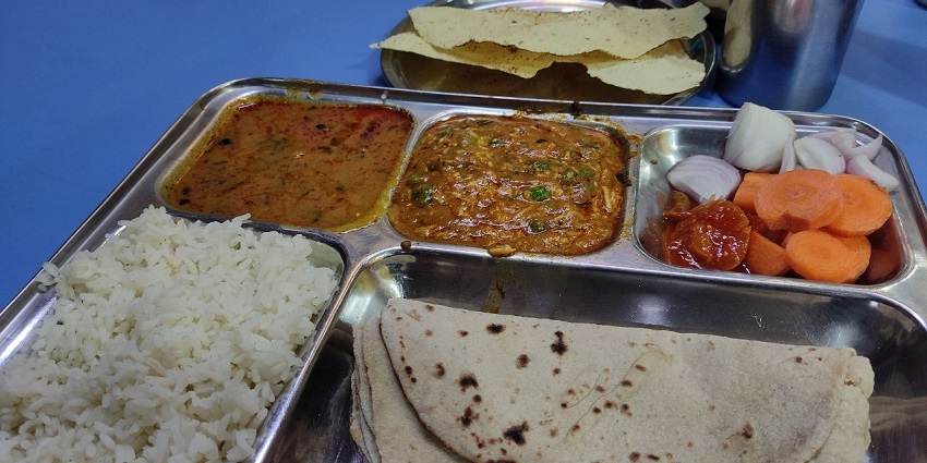 An Indian Thali featuring a variety of traditional dishes, including rice, chapati, curry, dal, vegetables, pickles
