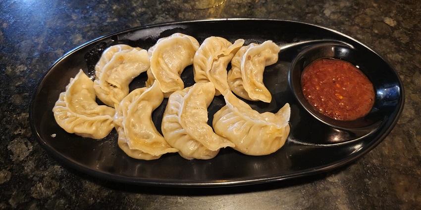 Momo with red sauce served on a black plate at a restaurant near Changu Lake in July.