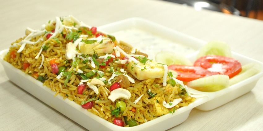 Kashmiri pulao of cooked rice and dry fruits served with cucumber and tomato salad