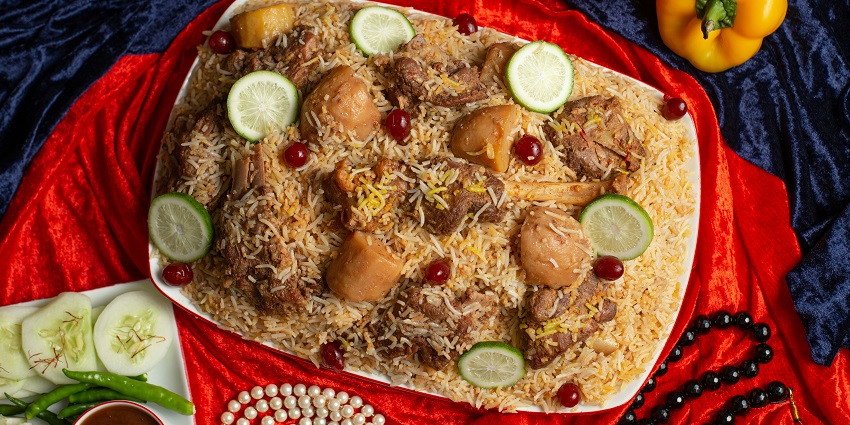 Chicken biryani served on a brass plate, garnished with mint leaves and whole spices.