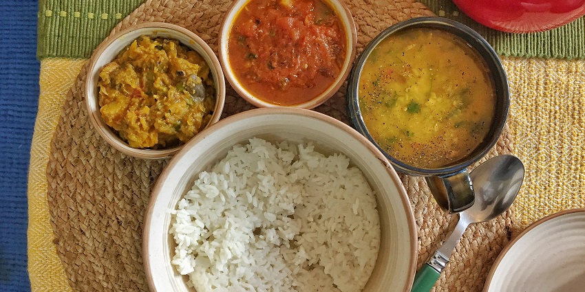 A plate of Odia cuisine including steamed rice, Dalma, Saaga, Alu Bharta, Amba Khatta, and a lime-chili salsa.