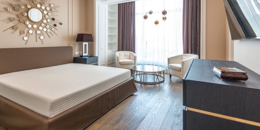Interior of a hotel room with a neatly made bed, blue pillows and two lamps on both sides.
