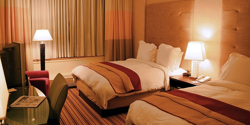 A lavish executive suite room with a view of a river from a glass window.