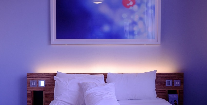 An image showing a hotel bedroom with a neatly made bed and modern interior design.