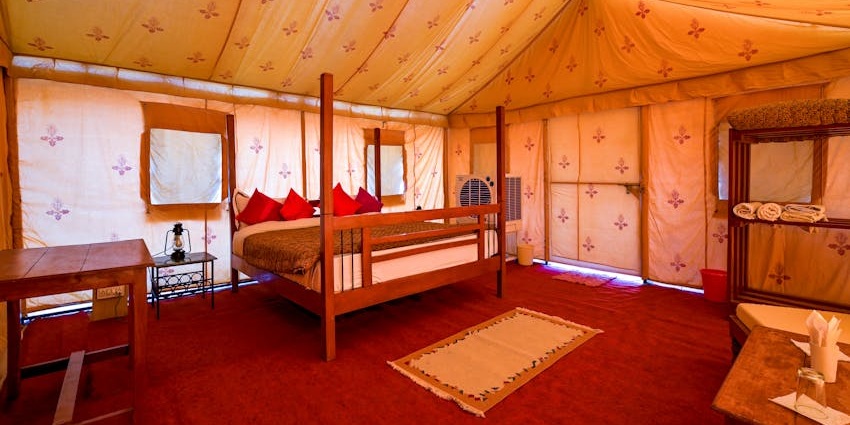 Tent guest house with a big bed, a water bottle on the table and wooden furniture