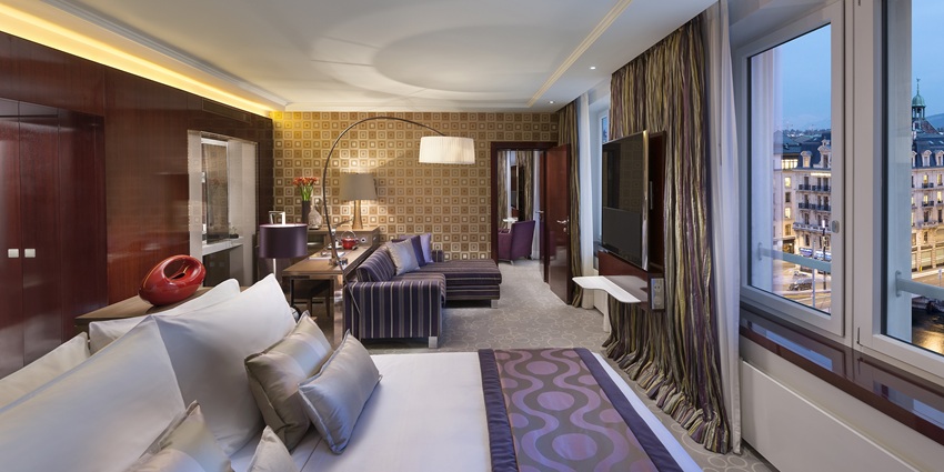 An image of a luxurious hotel room features elegant decor, plush bedding, and city views.