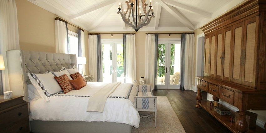 An image of a cosy bedroom featuring a headboard bed, and vaulted ceiling with beams.