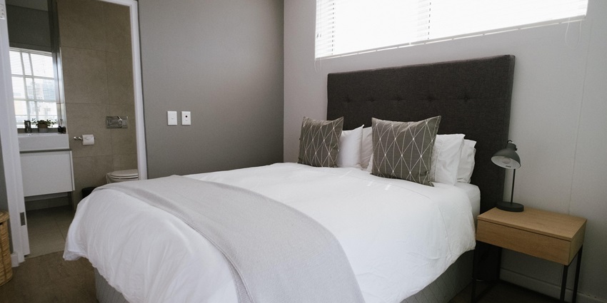Image of a well-furnished hotel bedroom with a bed, seating area, and lighting fixtures.