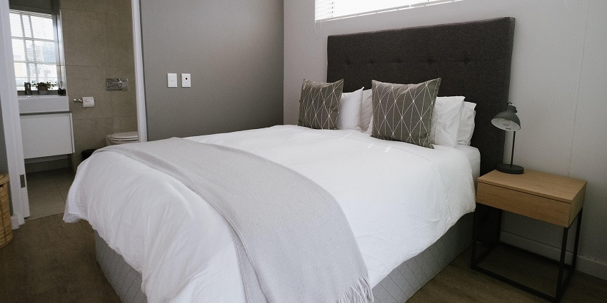 An image showing a hotel bedroom with furniture, a bed, and decorative interior elements.