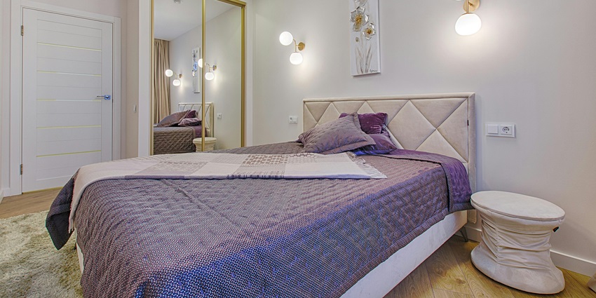 An image of a bedroom with a padded headboard, purple quilt - National Museum Colombo