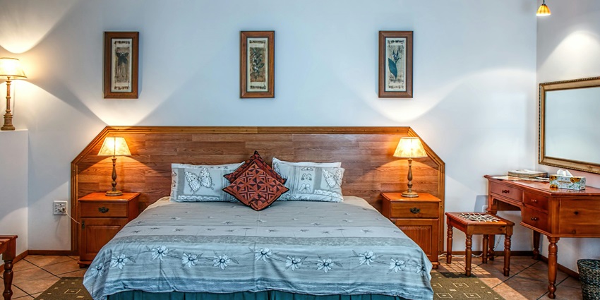 An image of a bedroom showcasing a light butterfly-themed bedspread, pillows, and lamps.