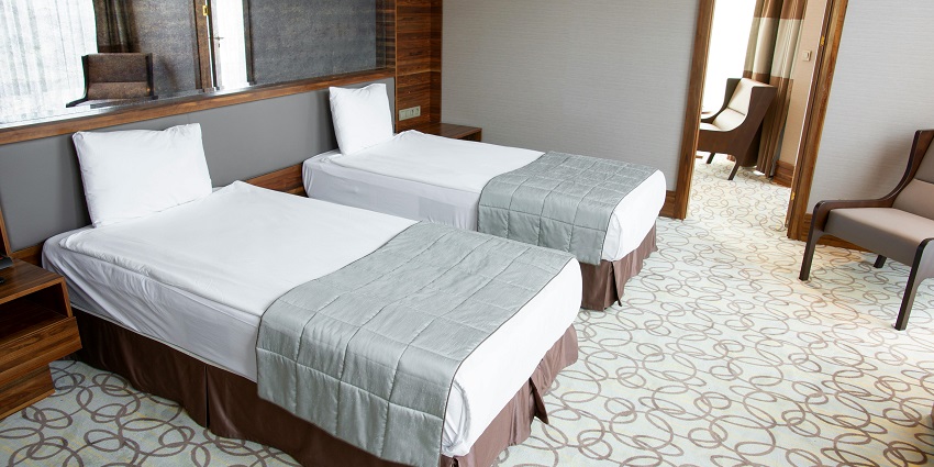 Hotel room with two separate beds, a big mirror near the bed, a chair and a unique floor