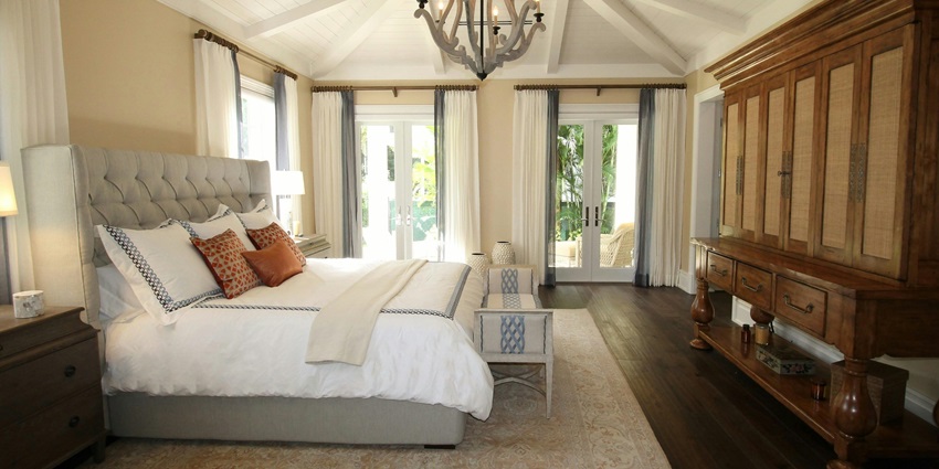 Interior of a hotel room with multiple doors, windows, a bed and wooden furniture