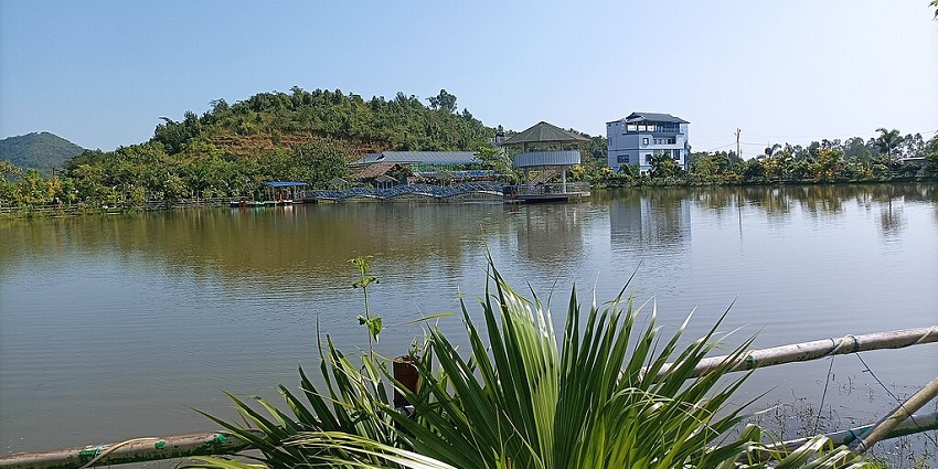 Floating homestays near the floating lake in Manipur with buildings, houses, green shorelines and mountains.