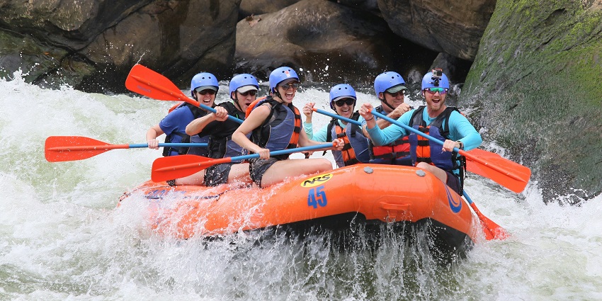 Image of a group of tourists on a raft water rafting and enjoying the thrill