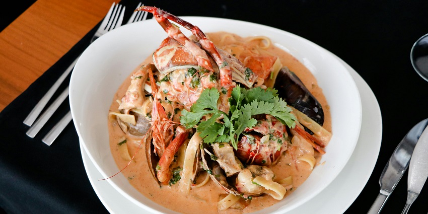A seafood dish consisting of crab, shrimp, mussels, and creamy sauce with fresh herbs.