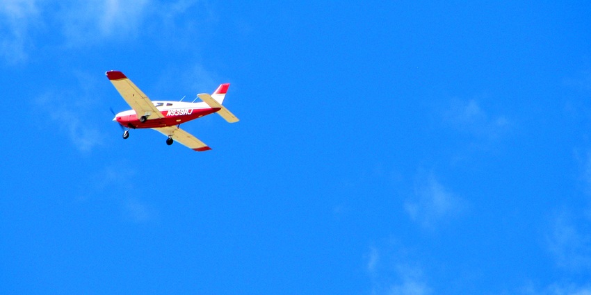 A red and white, single-engine airplane flying in the clear blue sky.