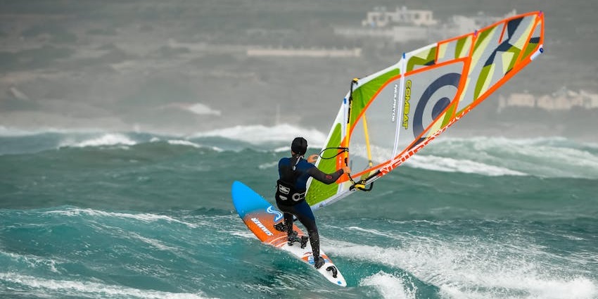Windsurfing In Margaret River navigating choppy turquoise waves, one of the best water sports in Australia.