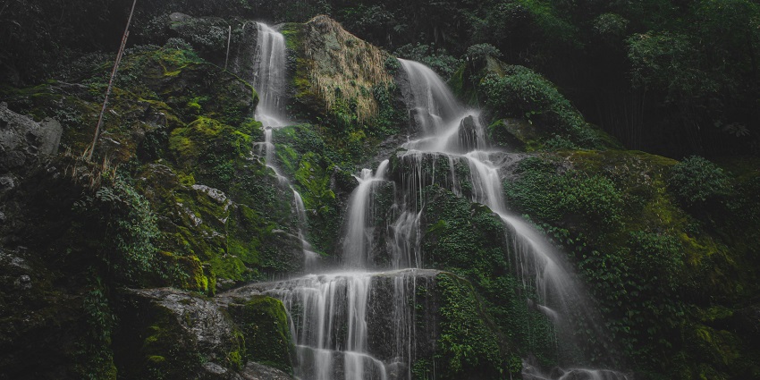 Waterfall in North Sikkim with water flowing on rocks surrounded by greenery.