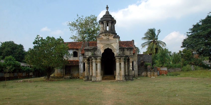 A frontal view of a historical building in Jaffna, surrounded by a lush green garden