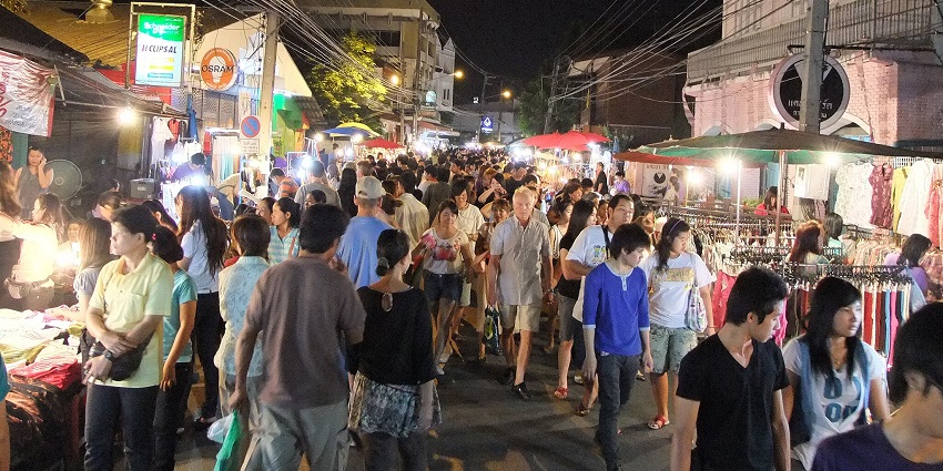 Lantern-lit WuaLai Walking Street market in Chiang Mai, filled with food stalls, souvenirs, and live performances.