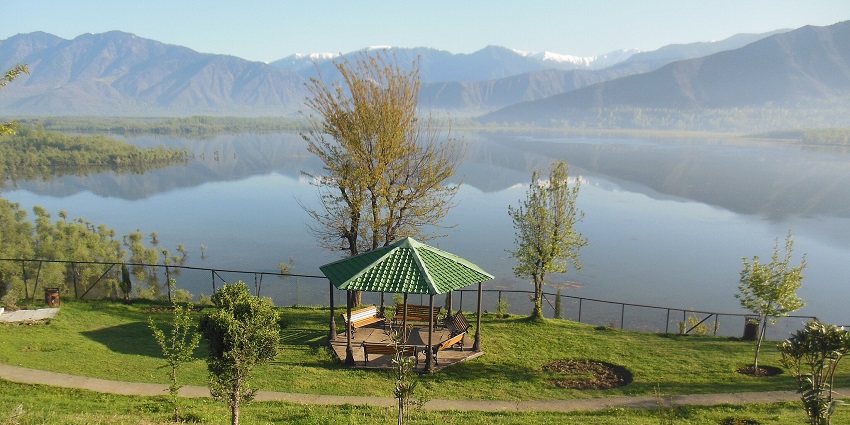 A stunning view of Wular Lake with tranquil waters reflecting the surrounding mountains.
