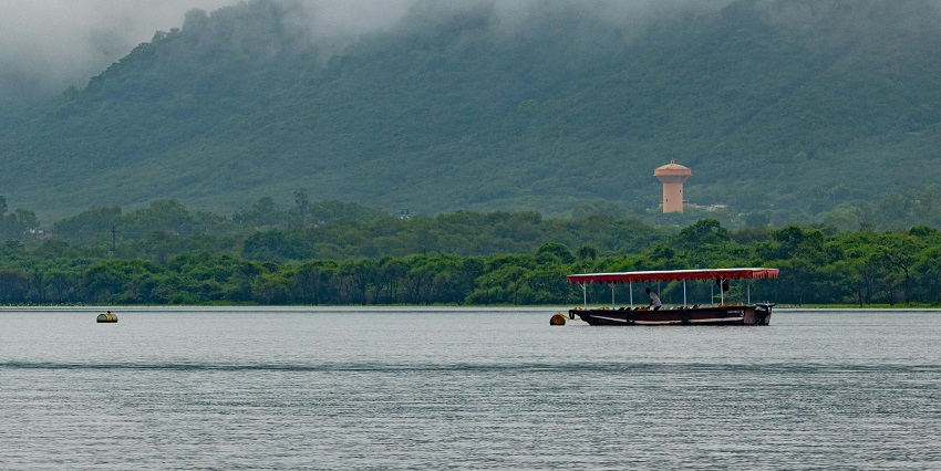 A picture of a boat sailing on a calm lake, resembling the scenic lakes in Indore at sunset