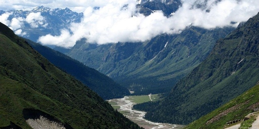 Yumthang valley with a small river flowing through the valley and the peak covered in snow