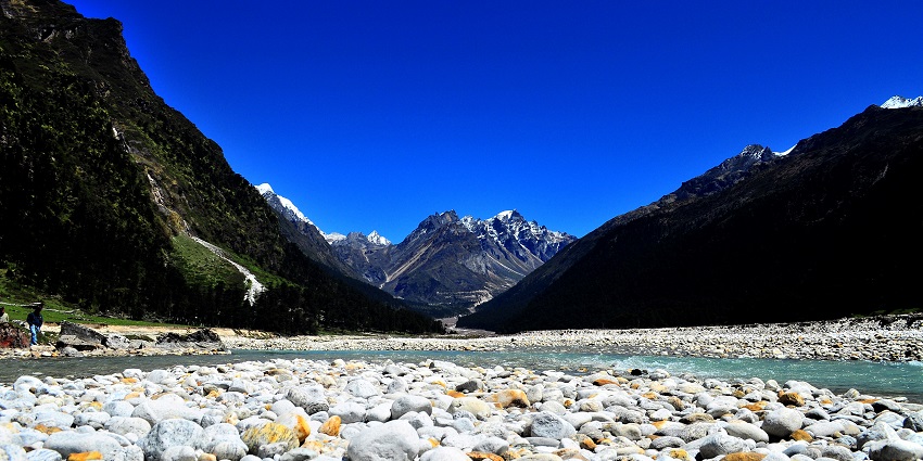 A bed of pebbles in the flowing Lachung River encircled by mountains in Yumthang Valley.