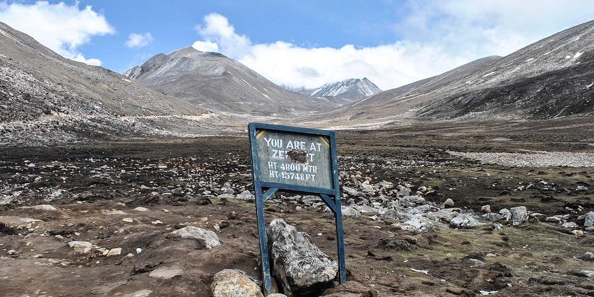Yumesamdong with a blue sign board, rocky sandy plains, and surrounded by the mountains