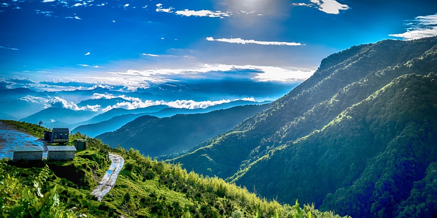 Zuluk village surrounded by green mountains with distant small houses under the blue sky.